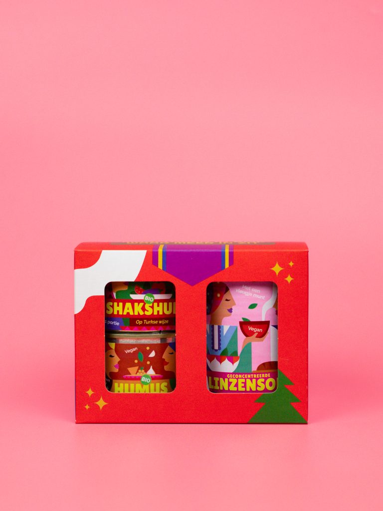 Rood kerstdoosje rode doos kerstdoos Mixblik feestelijk cadeau vegetarisch internationaal eten roze achtergrond Linzensoep Shakshuka Hummus Humus